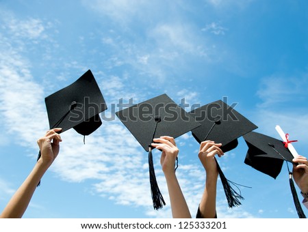 Many hand holding graduation hats on background of blue sky.