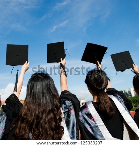 Many hand holding graduation hats on background of blue sky.