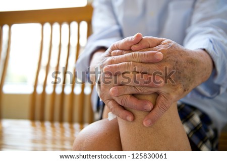 Old man sitting with his hands on knee.