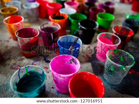 multicolored paint in different cups on the ground.