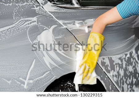 hand hold yellow sponge over the car for washing.