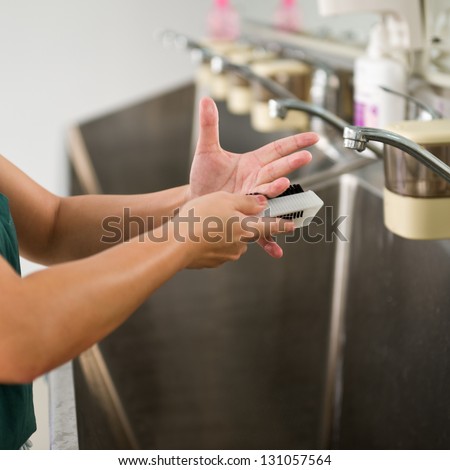 Female doctor washing hands before operation.