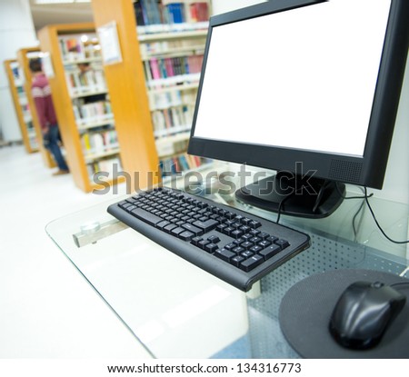 Computer In A Library With Many Books And Shelves In The Background.