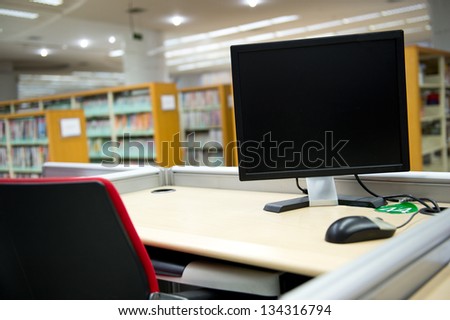 computer in a library with many books and shelves in the background.