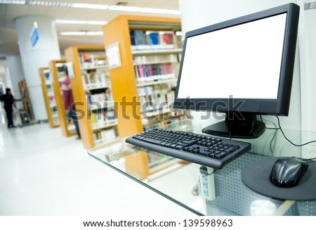 computer in a library with many books and shelves in the background.