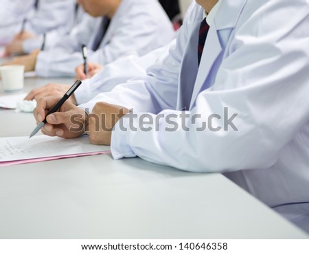 Group of doctors writing at a conference.