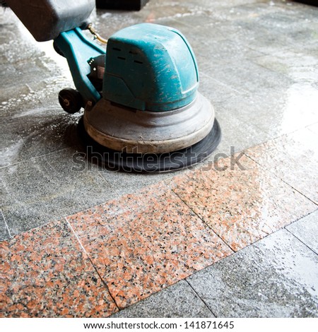 People cleaning floor with machine.