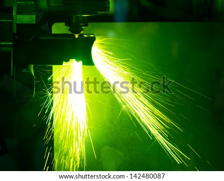 Industrial laser cutter with sparks.