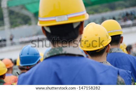 Rear view of many construction workers with helmet.