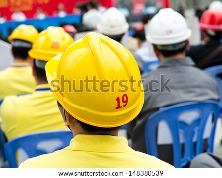 Rear view of many construction workers with helmet.