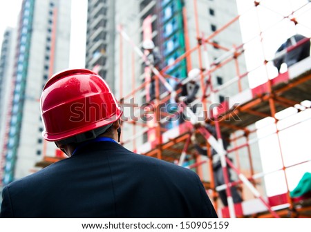 Rear view of builder inspector checking a construction site works.