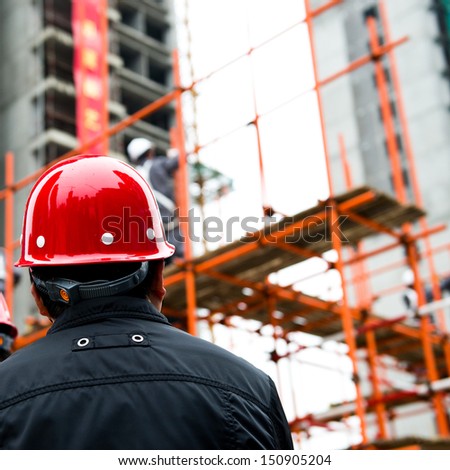 Rear view of builder inspector checking a construction site works.