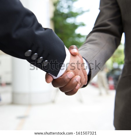 African businessman\'s hand shaking white businessman\'s hand  making a business deal.