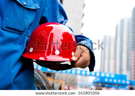 Worker holding a helmet with background of  blurred construction site.