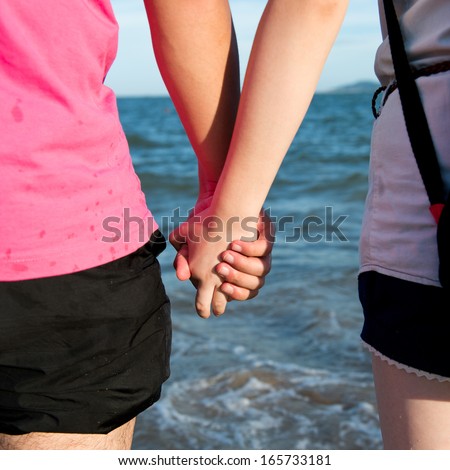 Summer couple holding hands in front of the sea.