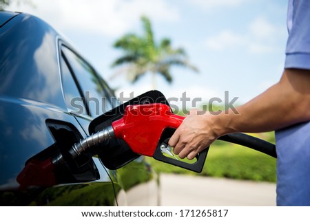 Hand refilling the car with fuel.