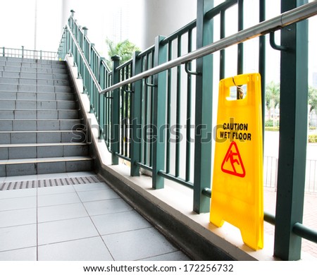Wet floor caution sign near the stairs.
