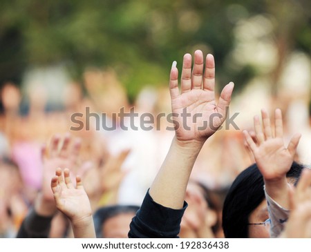 Many hands raised in a crowd of people