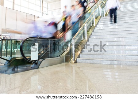 Group of businesspeople moving down on escalator in office. blurred motion.