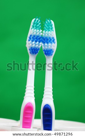 Her toothbrush and his toothbrush on green background