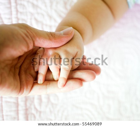 detail of new born babies tiny hand resting in adult hand.