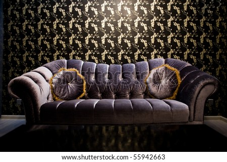 Modern purple sofa with two cushions in front of beautiful wallpaper.