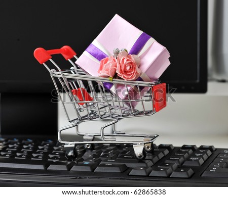 Shopping cart with gift box on the keyboard of computer.
