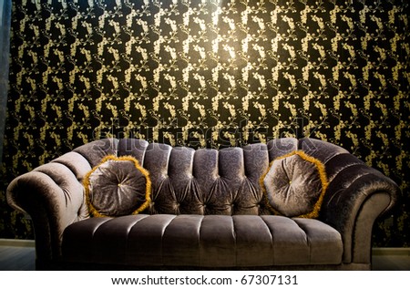 Modern purple sofa with two cushions in front of beautiful wallpaper.