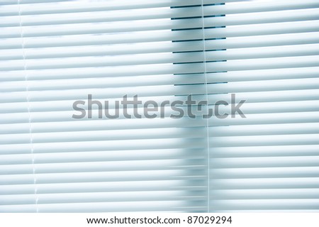 background image of white mini blinds inside home closed.