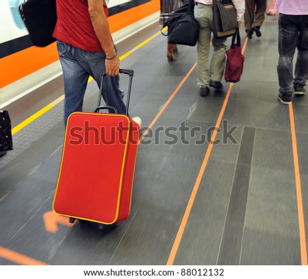 Businessman pulling trolley at train station.