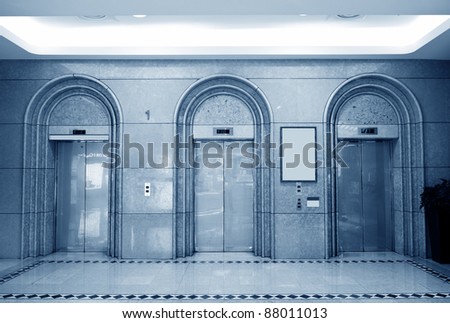 Three elevator doors in corridor of office building