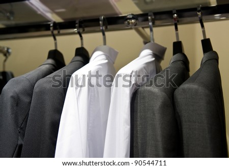 row of cloth hangers with shirts and suit.