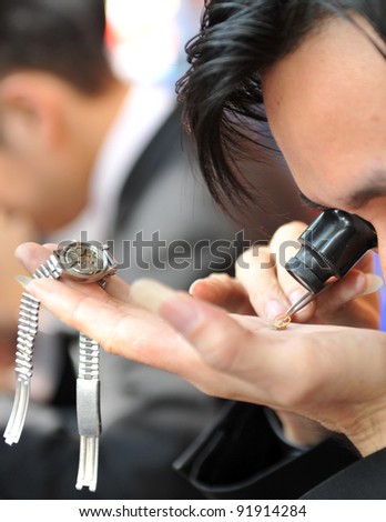 A watchmaker or repair man in action, viewing very closely a watch.