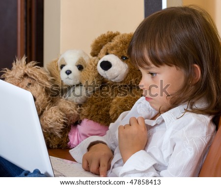 The concentrated girl works behind a portable computer. Soft toys observe of its work.