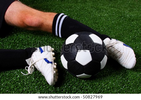 Soccer ball being kicked with soccer boots (football) in a slide tackle on green grass (artificial turf)