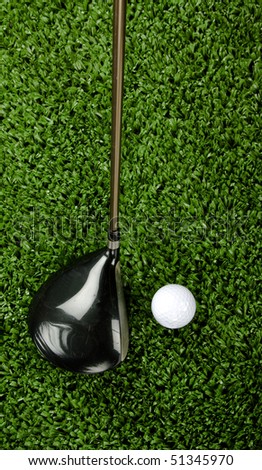 Golf club (driver) shot from above being teed up next to a white golf ball