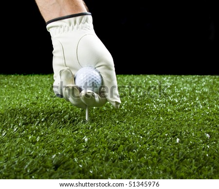 golfer wearing a golf glove putting a ball and a tee in the ground before teeing off, copy space.