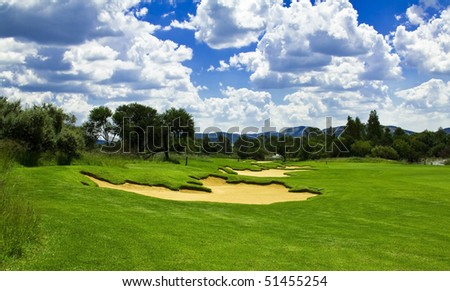Golf course with green grass sand traps(bunkers) and river in the distance with a perfect sky