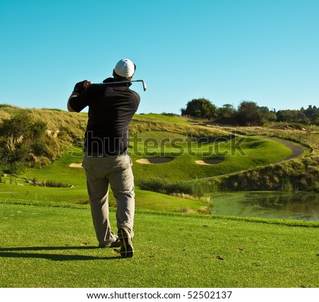 Golfer (player) standing on tee facing a green playing golf hitting a ball to the hole