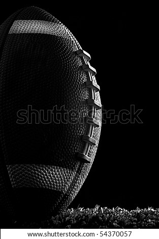 American football close up at night on flood lit green field (dark mood) in kicking position black and white