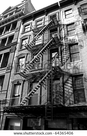 old urban building with fire escape in new york , monotone