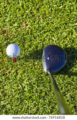 white golf ball on red tee in grass with driver close up ,ready to be hit, shot from above