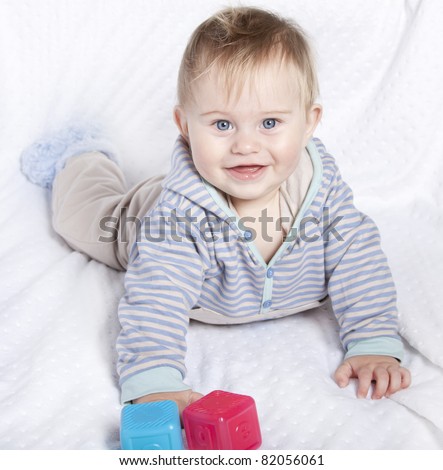 Beautiful little baby boy playing on white blanket with generic abc blocks 9 months old