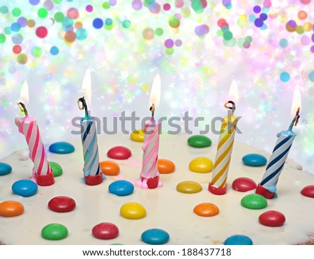 Cake With Burning Candles,  five multi-colored candles. Background with colorful lights.