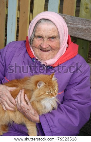 A portrait of a very old woman, 91 years old near his house, has control over a red cat
