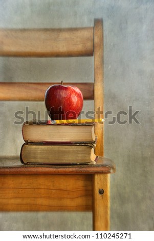 Apple and old books on school chair with vintage feel