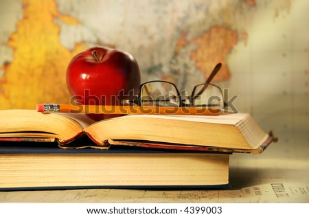 Old books with red apple and glasses on study desk