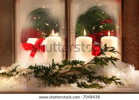 Three white candles in a frosted window