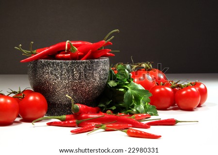 Red peppers and tomatoes with granite bowl on dark background