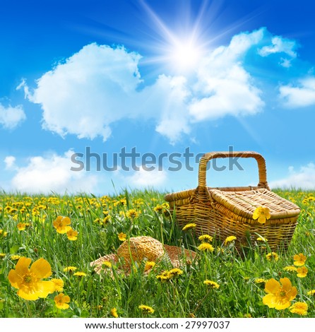 Summer picnic basket with straw hat in a field of dandelions